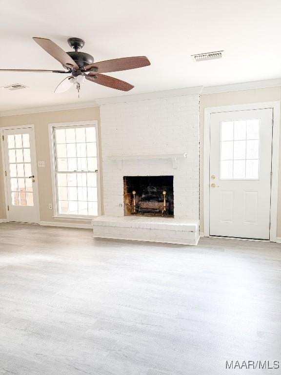 unfurnished living room with crown molding, a fireplace, light hardwood / wood-style floors, and ceiling fan