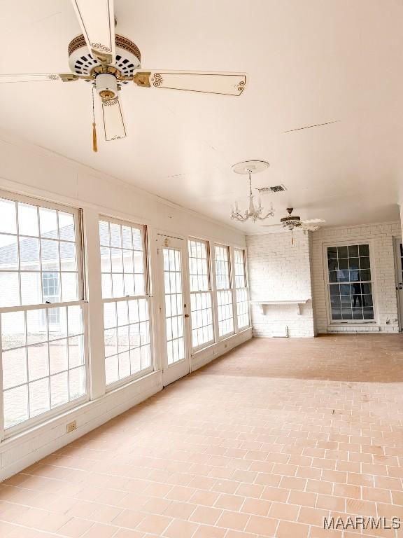 unfurnished sunroom with a wealth of natural light, a fireplace, and ceiling fan