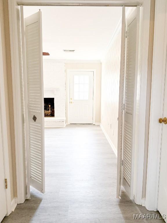 corridor featuring crown molding and light hardwood / wood-style flooring