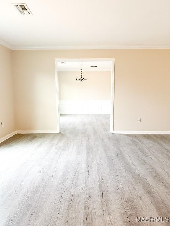 unfurnished room with an inviting chandelier, crown molding, and light hardwood / wood-style floors