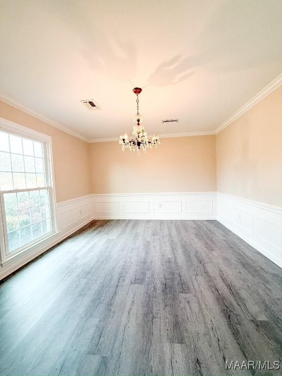 spare room with hardwood / wood-style floors, ornamental molding, and a chandelier