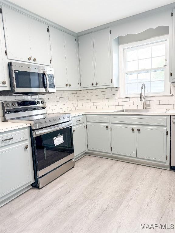 kitchen featuring sink, backsplash, stainless steel appliances, and light hardwood / wood-style floors