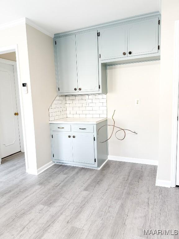 laundry room featuring ornamental molding and light hardwood / wood-style floors