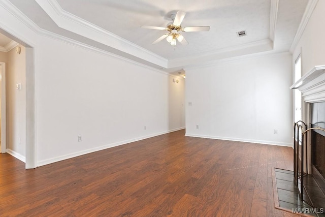 unfurnished living room featuring dark wood-type flooring, ceiling fan, ornamental molding, and a raised ceiling