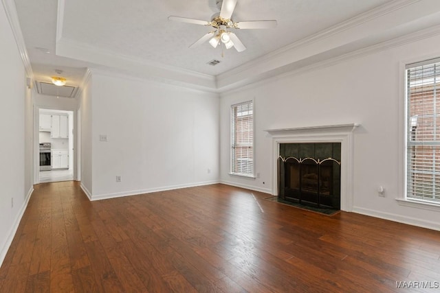 unfurnished living room featuring dark wood-type flooring, a fireplace, a tray ceiling, and crown molding