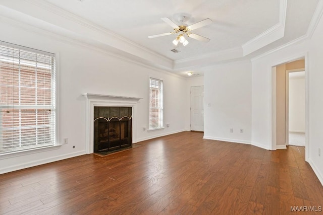 unfurnished living room featuring dark wood-type flooring, a tile fireplace, ceiling fan, ornamental molding, and a raised ceiling