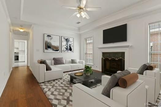 living room featuring a raised ceiling, crown molding, hardwood / wood-style flooring, and ceiling fan