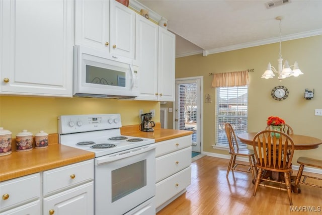 kitchen featuring crown molding, hanging light fixtures, white appliances, and white cabinets