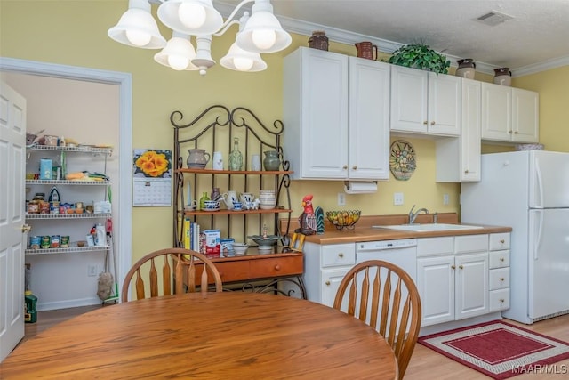 kitchen with decorative light fixtures, white cabinetry, sink, ornamental molding, and white appliances