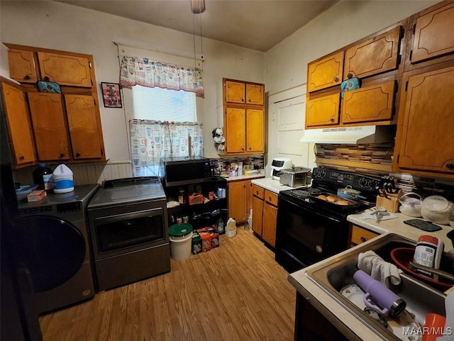 kitchen featuring pendant lighting, sink, independent washer and dryer, black appliances, and light wood-type flooring