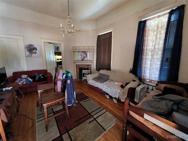 living room featuring hardwood / wood-style flooring, a tile fireplace, and a notable chandelier