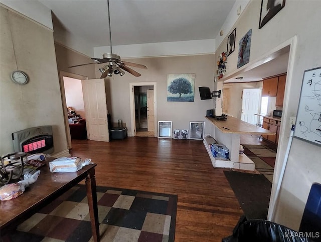 living room featuring dark wood-type flooring, ceiling fan, and heating unit