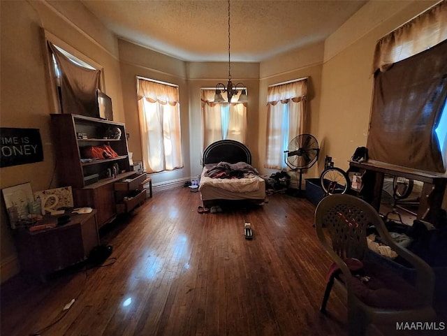 living area with a wealth of natural light, dark wood-type flooring, a chandelier, and a textured ceiling