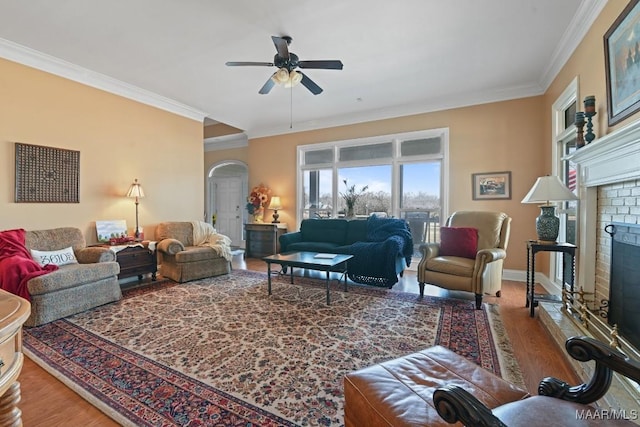 living room featuring hardwood / wood-style flooring, ornamental molding, ceiling fan, and a fireplace