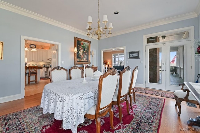 dining space with french doors, ornamental molding, wood-type flooring, and a chandelier