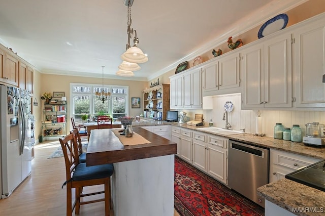 kitchen featuring decorative light fixtures, white cabinetry, sink, a center island, and stainless steel appliances