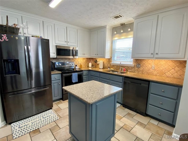 kitchen featuring sink, appliances with stainless steel finishes, backsplash, a center island, and white cabinets