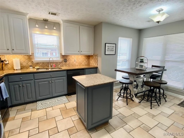 kitchen with sink, white cabinetry, tasteful backsplash, black dishwasher, and a kitchen island