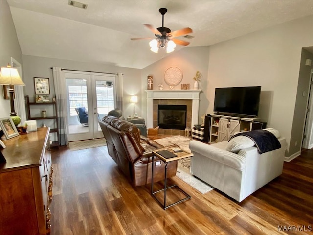 living room featuring dark wood-type flooring, french doors, vaulted ceiling, ceiling fan, and a fireplace