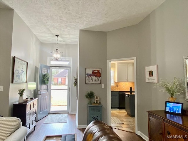 foyer featuring a notable chandelier, a textured ceiling, and light wood-type flooring