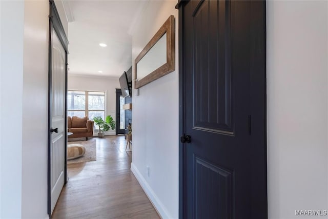 hallway with ornamental molding and light wood-type flooring