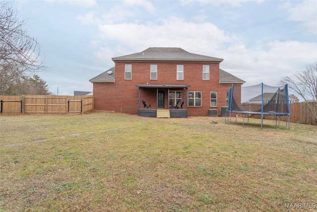 back of house with central AC, a yard, and a trampoline