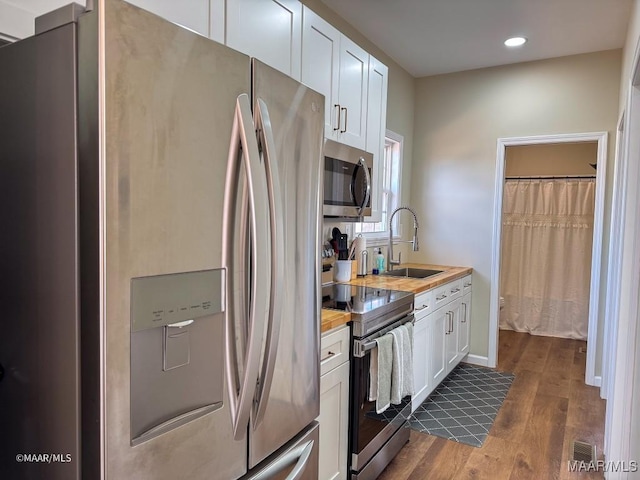 kitchen featuring sink, dark hardwood / wood-style flooring, appliances with stainless steel finishes, white cabinetry, and wood counters