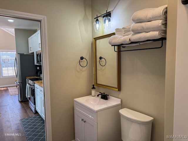 bathroom with vaulted ceiling, vanity, toilet, and hardwood / wood-style floors