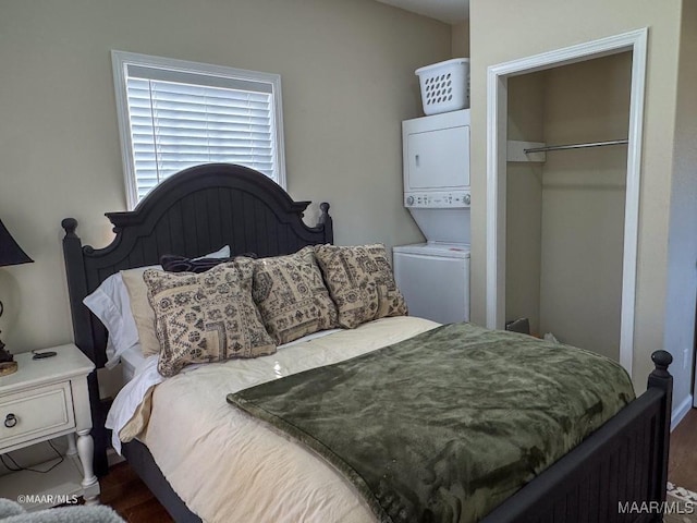 bedroom with dark hardwood / wood-style floors and stacked washing maching and dryer