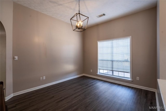 empty room with dark hardwood / wood-style floors, a textured ceiling, and a notable chandelier