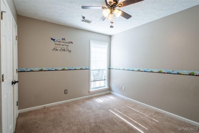 carpeted empty room with ceiling fan and a textured ceiling