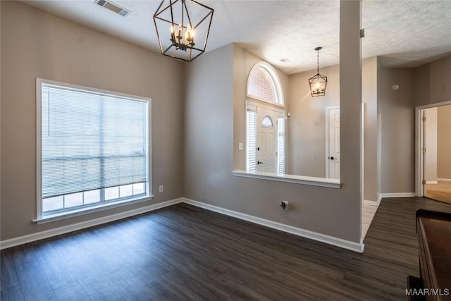 foyer entrance with a chandelier, a textured ceiling, and dark hardwood / wood-style flooring