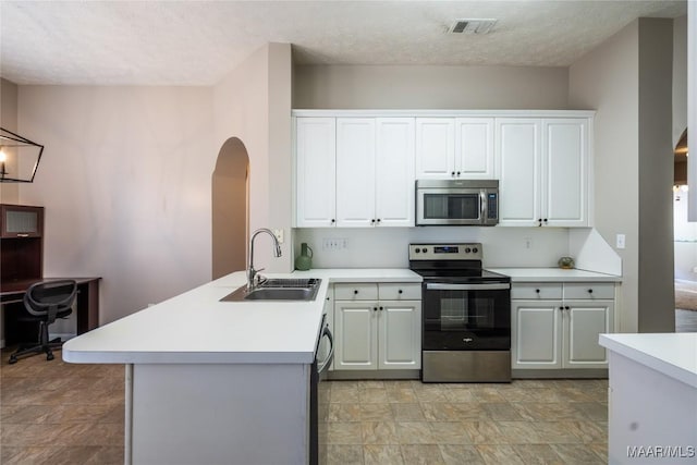 kitchen with sink, white cabinetry, a textured ceiling, appliances with stainless steel finishes, and kitchen peninsula