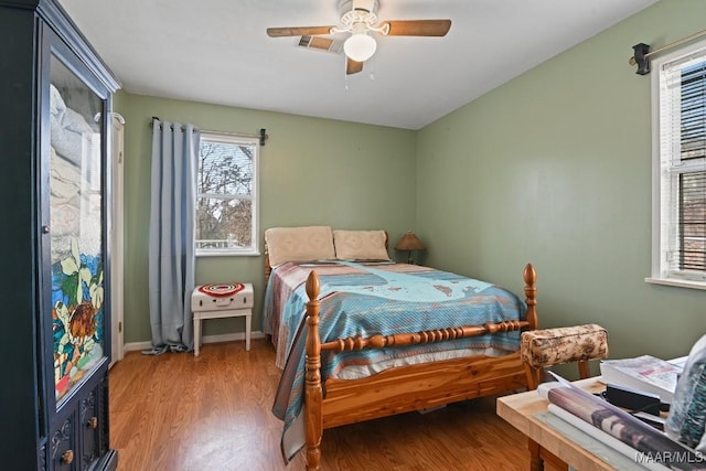 bedroom featuring a ceiling fan, baseboards, visible vents, and wood finished floors