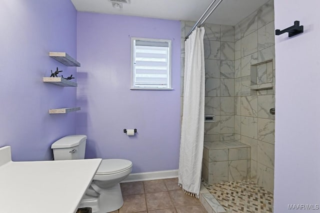 bathroom with toilet, a shower stall, baseboards, and tile patterned floors