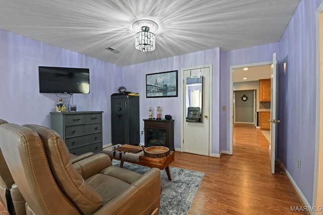 living area with light wood-type flooring, visible vents, and baseboards