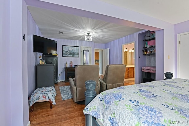 bedroom with ensuite bathroom and wood finished floors