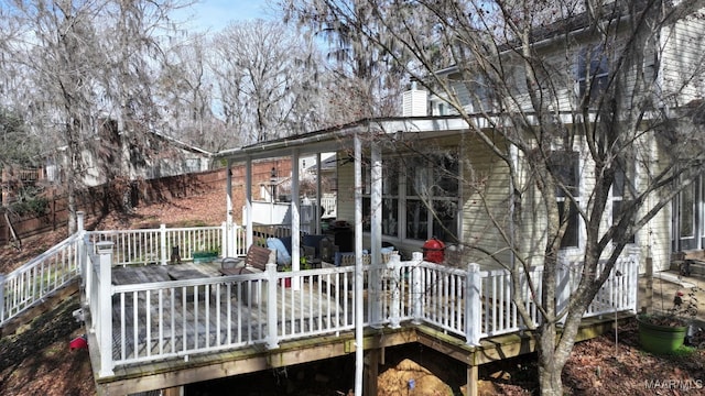 rear view of house featuring a chimney, a wooden deck, and fence