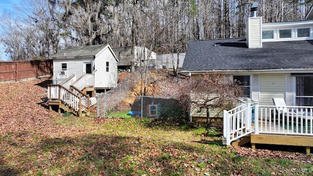 view of side of property featuring an outbuilding, a fenced backyard, a chimney, and roof with shingles