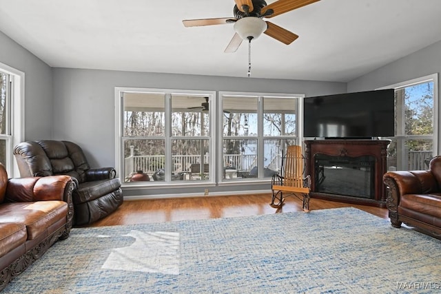 living room featuring a glass covered fireplace, light wood-style flooring, and a ceiling fan