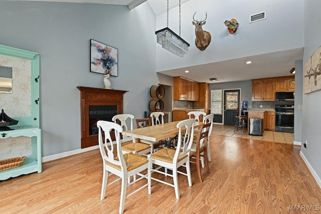 dining area with baseboards, a fireplace, visible vents, and light wood-style floors