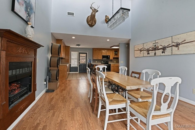 dining space featuring light wood-type flooring, a fireplace, visible vents, and baseboards