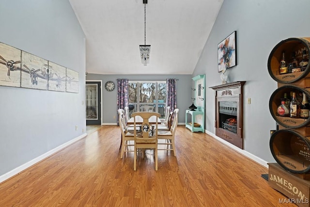 dining area featuring high vaulted ceiling, light wood-type flooring, and baseboards