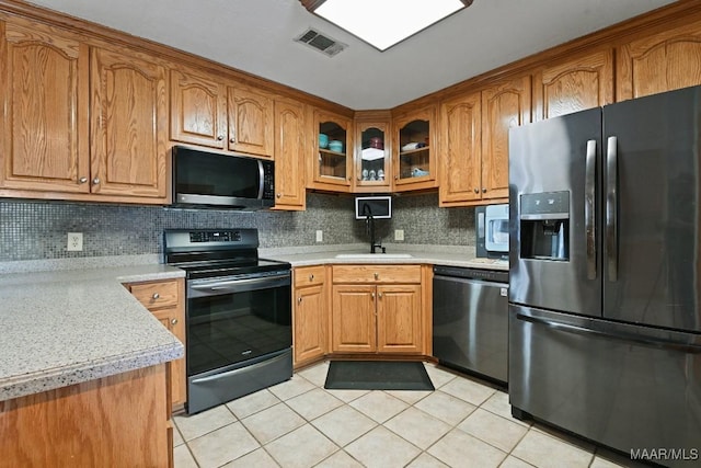 kitchen featuring visible vents, glass insert cabinets, brown cabinets, stainless steel appliances, and a sink