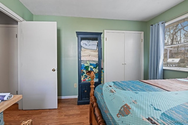 bedroom with a closet, baseboards, and wood finished floors