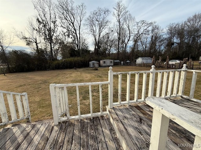 wooden deck featuring a shed and a lawn