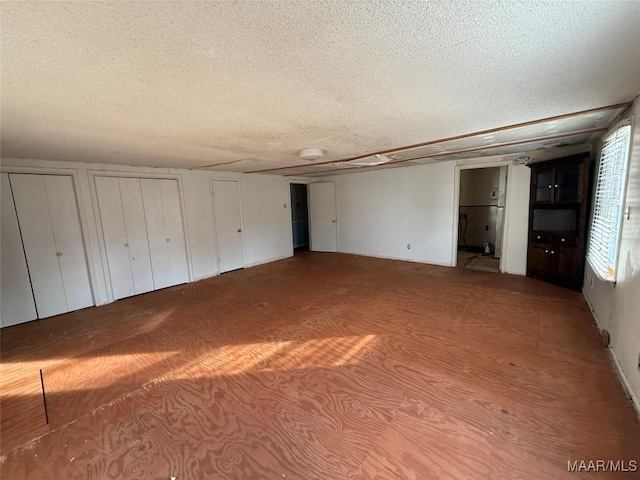 unfurnished bedroom with two closets and a textured ceiling