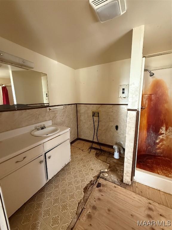 bathroom featuring tile walls, vanity, lofted ceiling, and walk in shower