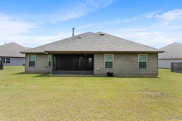 back of house featuring a yard, roof with shingles, and a sunroom