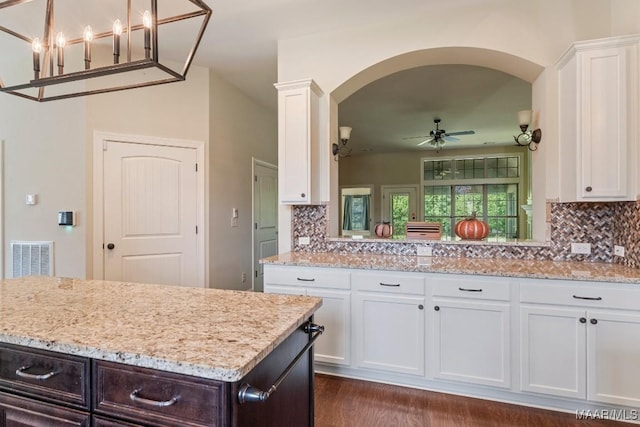 kitchen with white cabinets, decorative backsplash, hanging light fixtures, ceiling fan, and light stone countertops